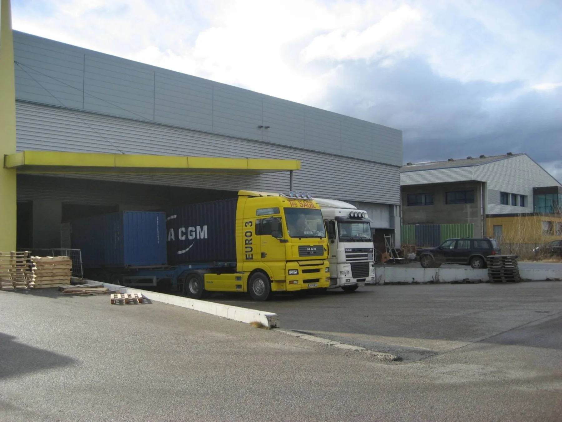 Camiones europeos y contenedor en un centro logístico